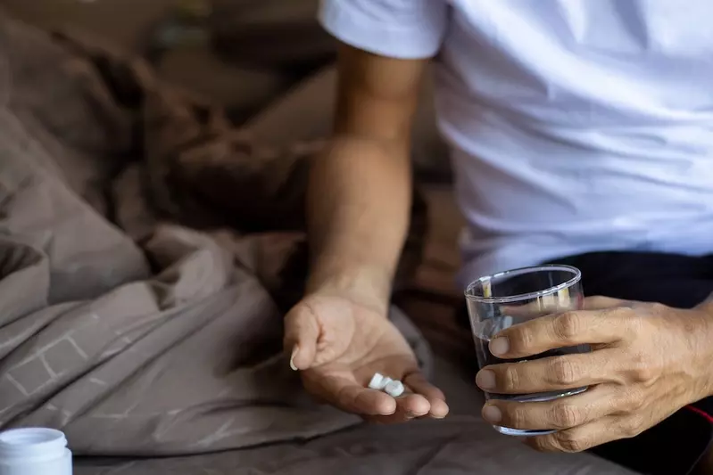 man taking pill in bed